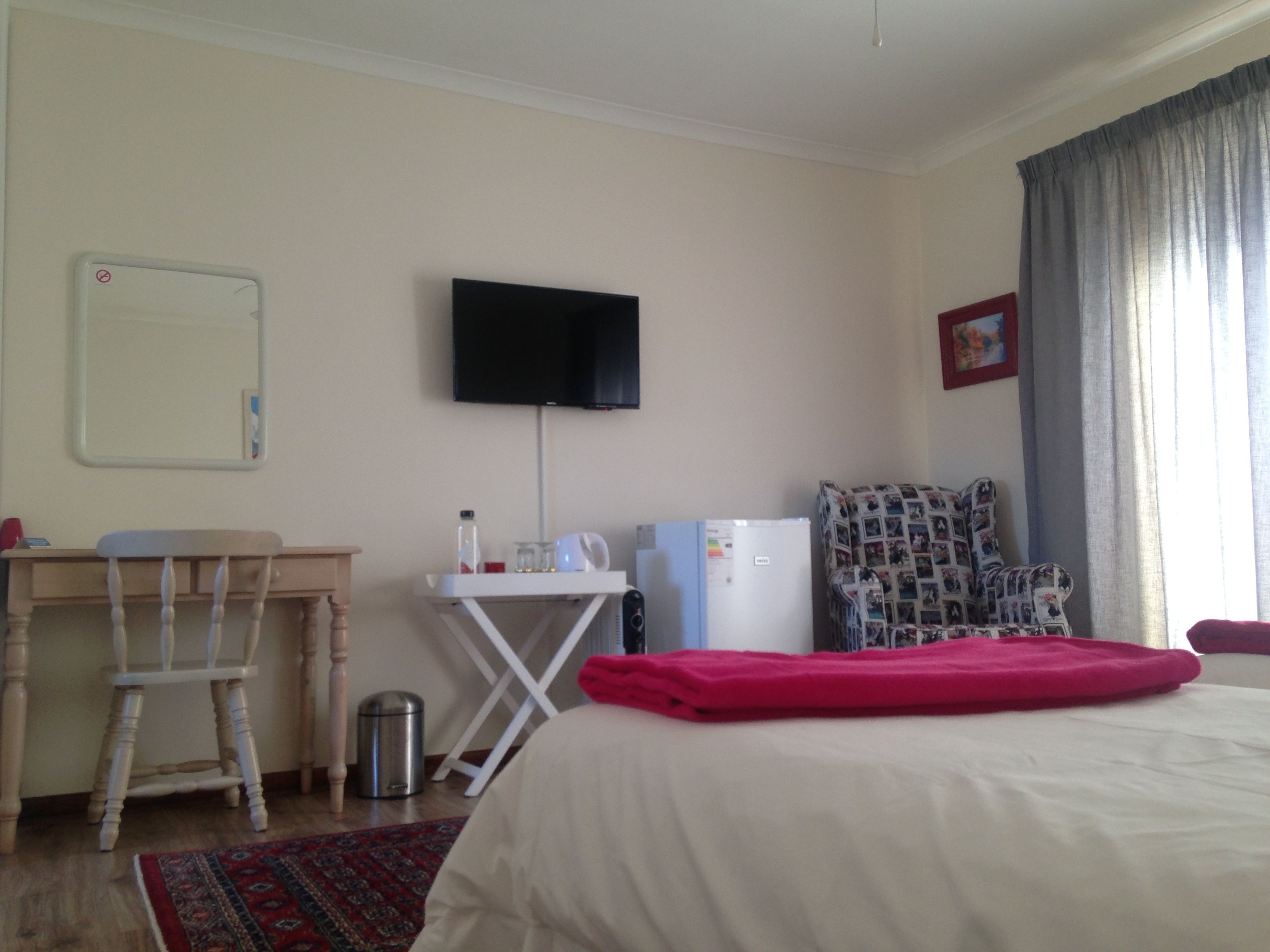Habitación de hotel con cama, escritorio, silla, televisor y una pequeña mesa.