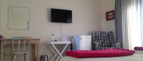 Habitación de hotel con cama, escritorio, silla, televisor y una pequeña mesa.