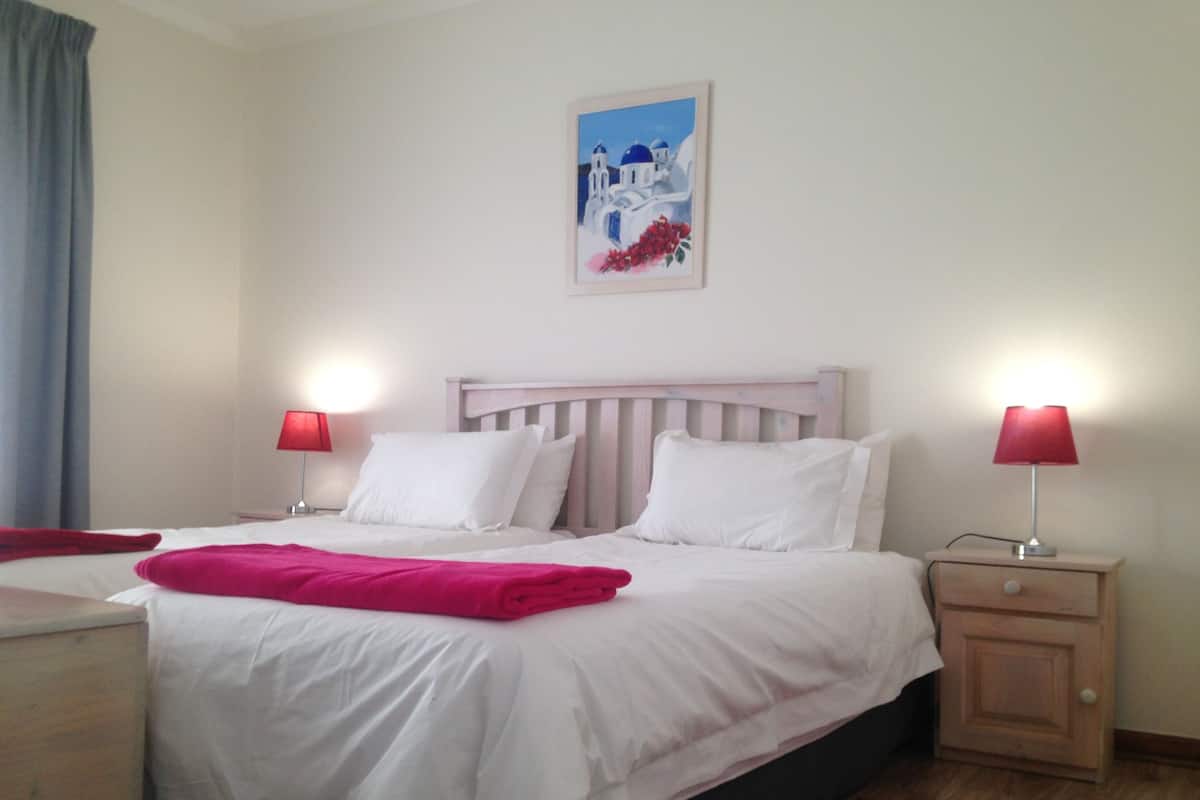 Une chambre à coucher avec un lit, deux tables de chevet, une commode, un tapis rouge et un tableau accroché au mur.