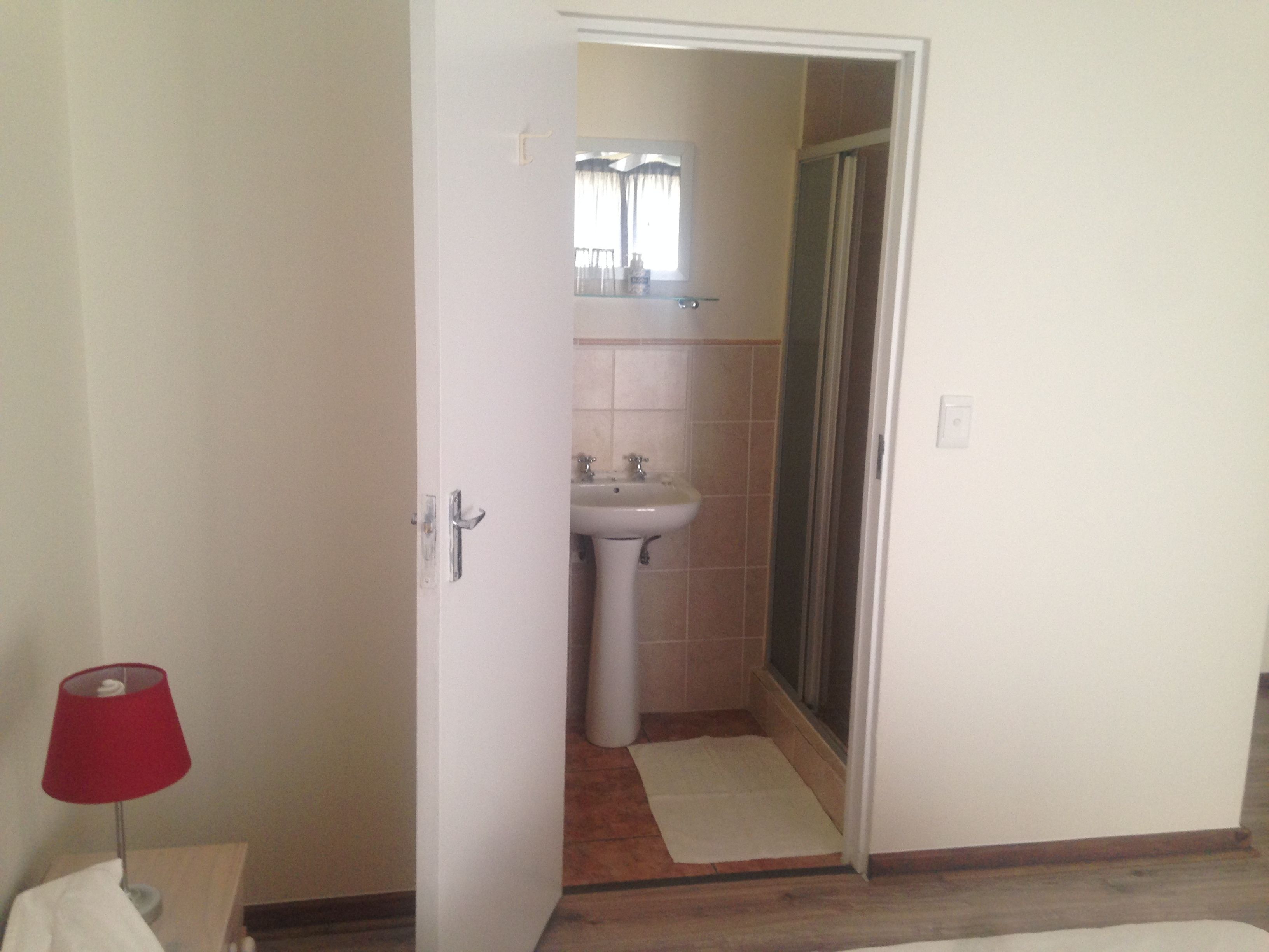 A bathroom with a sink, mirror, and shower.