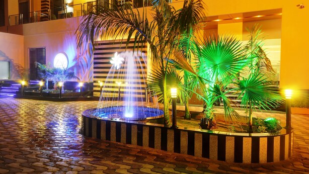 Un patio con una fuente, palmeras y un edificio con balcones.
