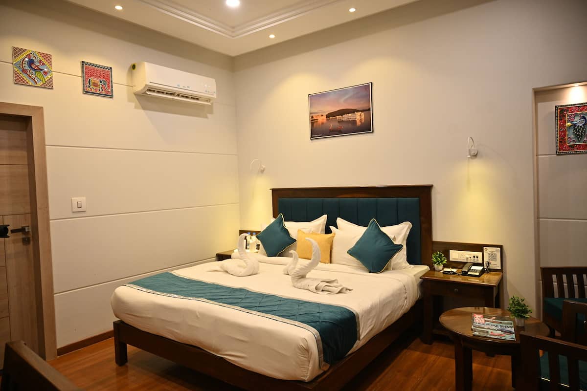 Una habitación de hotel ordenada con cama, mesitas de noche, escritorio y una silla.