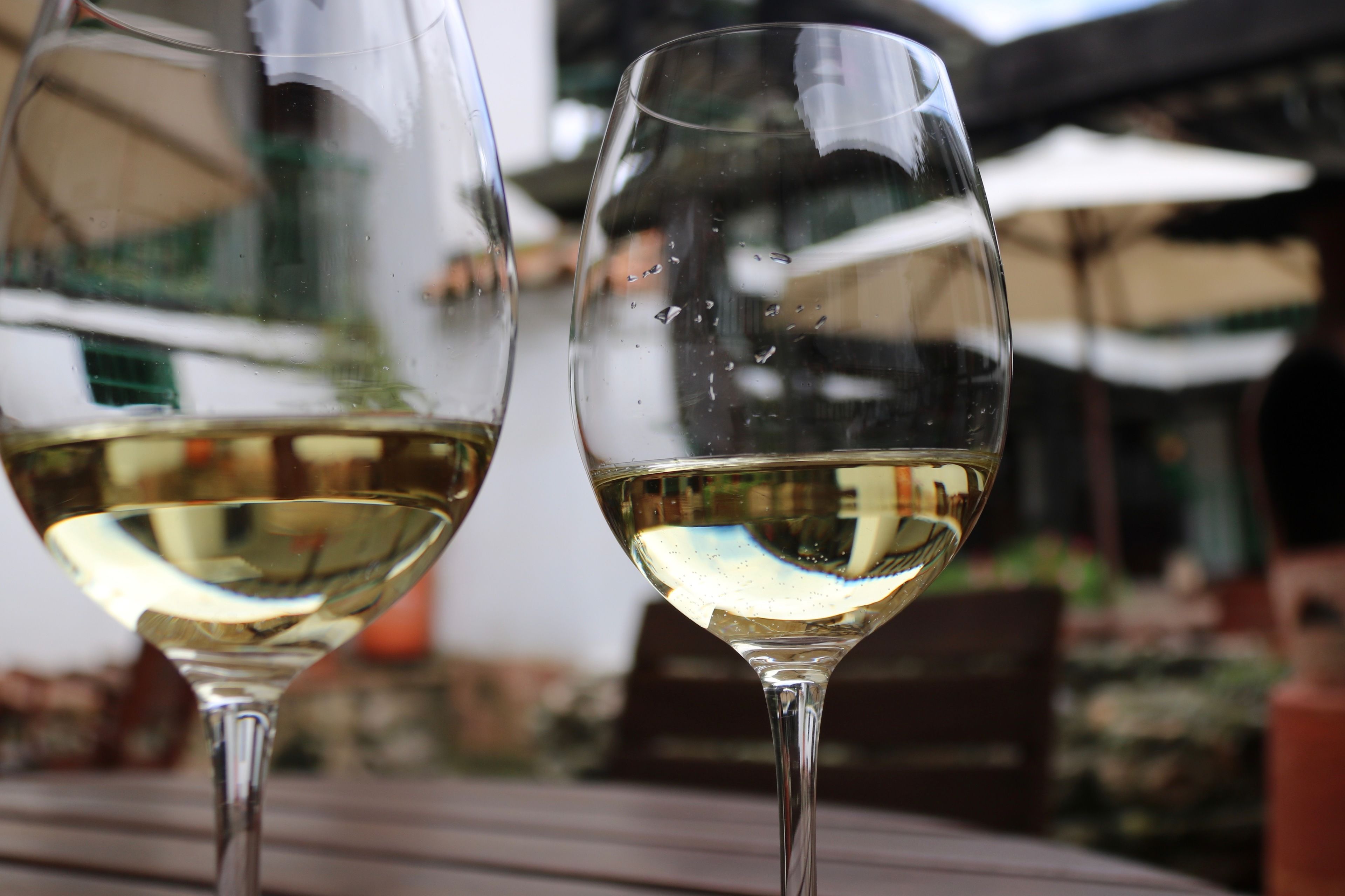 Two wine glasses on a table with a blurred outdoor background.