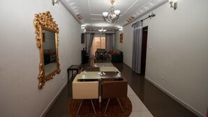 A hallway with a dining table and chairs, a large ornate mirror, and a chandelier. - The Address Denver Residence (Douala)
