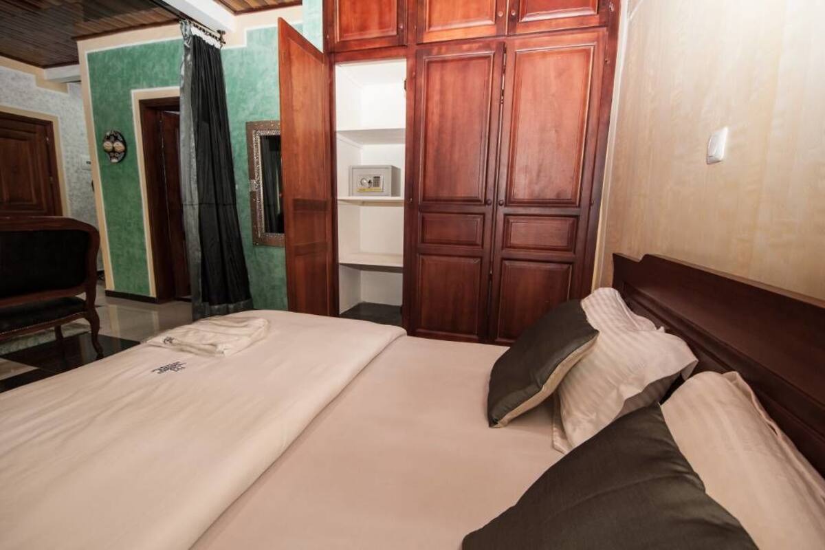 Une chambre à coucher avec un lit, une armoire en bois et un petit meuble.