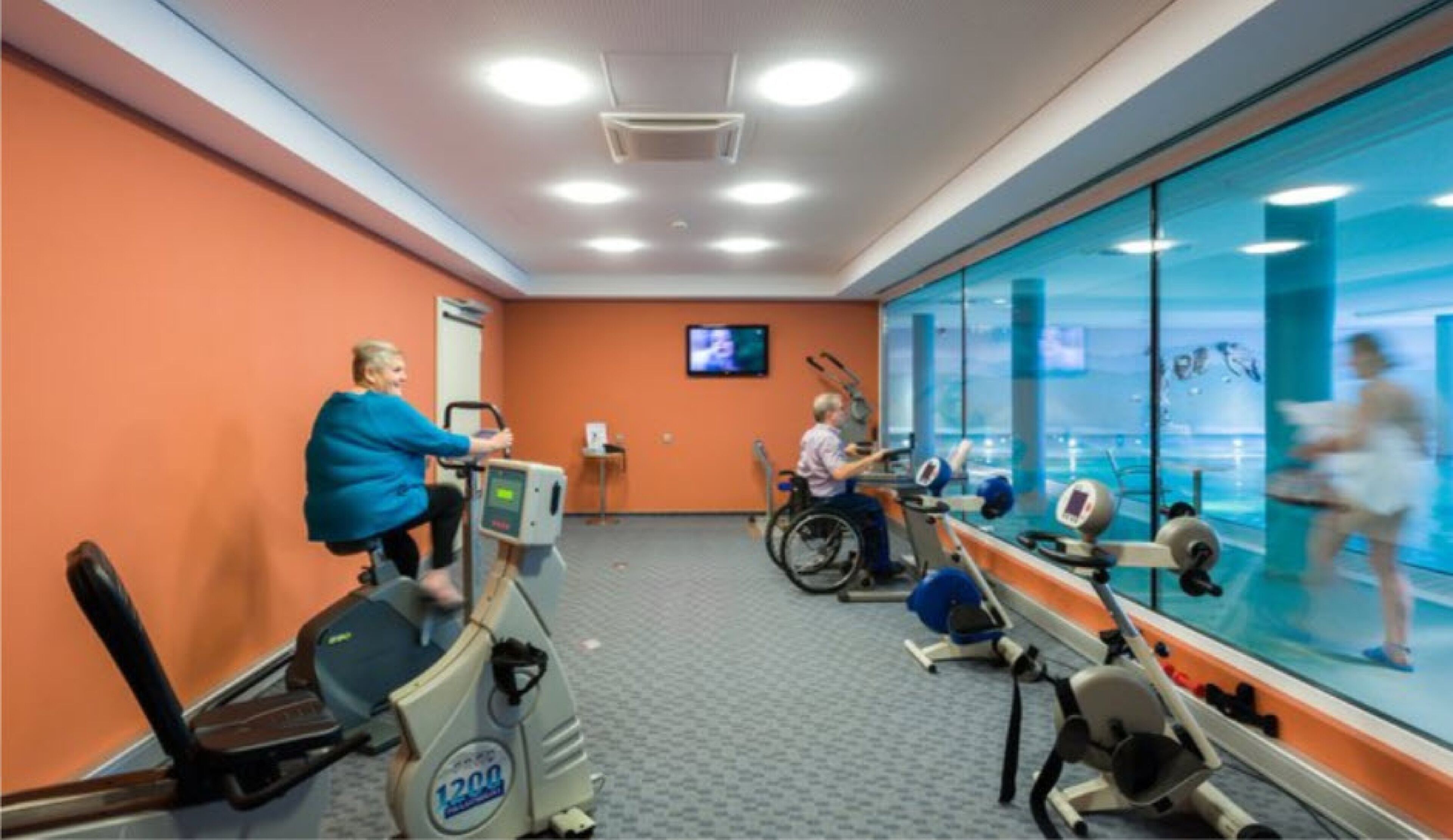 Een fitnessruimte met cardioapparatuur, een televisie en een groot raam met uitzicht.