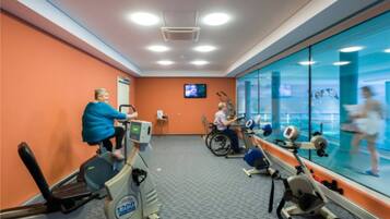 Een fitnessruimte met cardioapparatuur, een televisie en een groot raam met uitzicht.