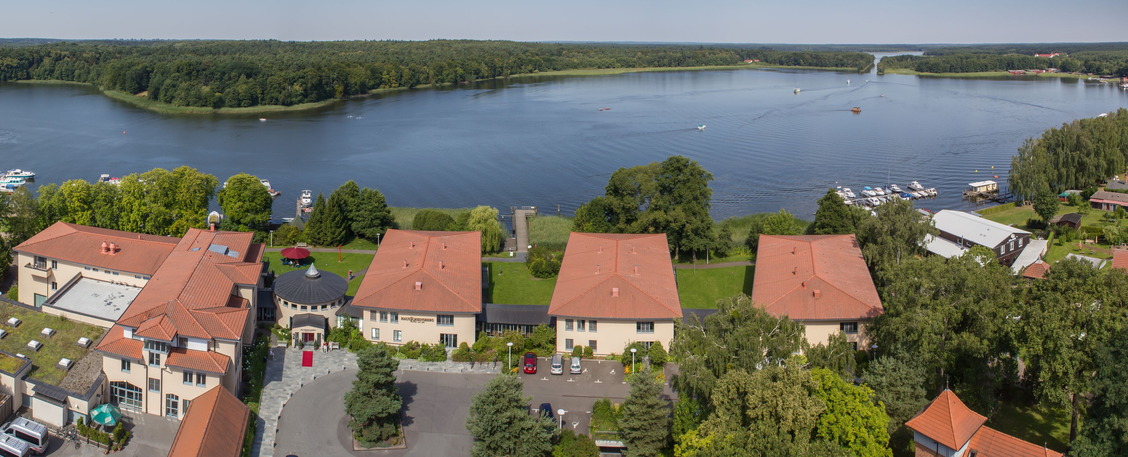 A lakeside property with multiple buildings, a parking area, and boats on the water.