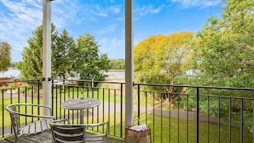 A balcony with a table and chairs, a bag, and a view of trees and a pathway.