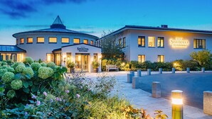 Ein Hotel mit einem runden Hauptgebäude und einem rechteckigen Anbau, beide mit beleuchteter Beschilderung.