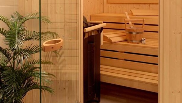 Una sauna de madera con bancos y un panel de vidrio.