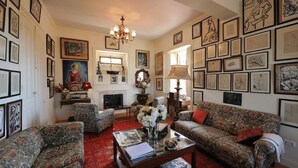 A traditional living room with a fireplace, patterned sofas, and a chandelier. - Shepinetree - Pinheira House (Sintra)