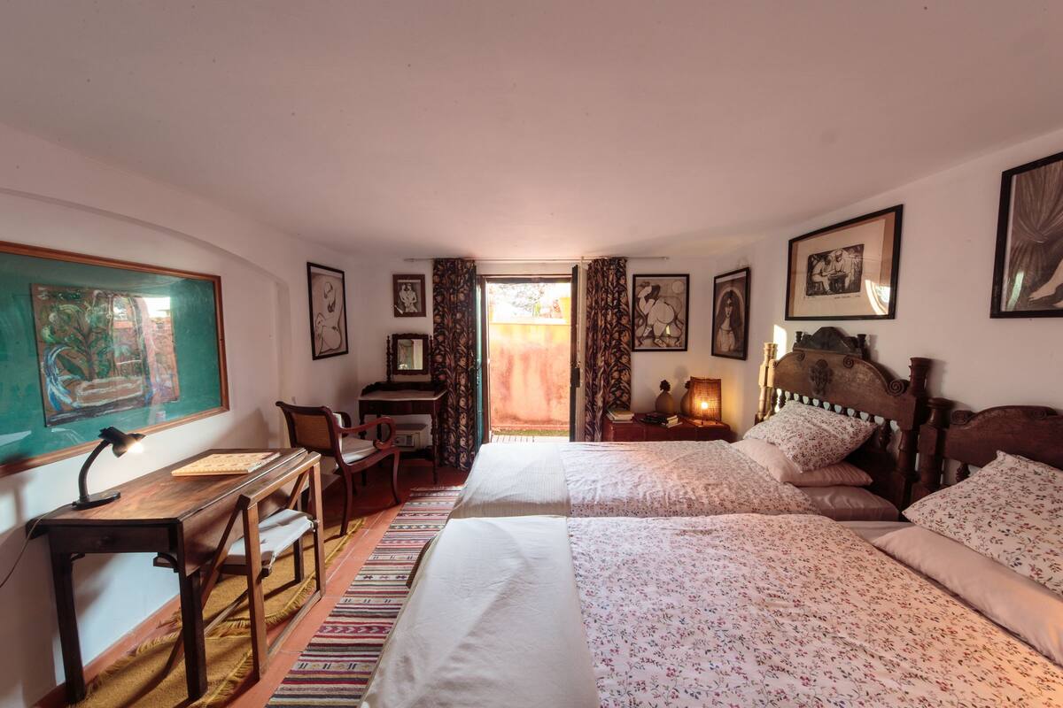 Een slaapkamer met twee bedden, een bureau en een stoel. Er hangen prestaties aan de muur en een raam met gordijnen.