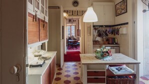 A kitchen with a hexagonal patterned floor, a dining area with a red carpet, and a chandelier. - Shepinetree - Pinheira House (Sintra)