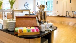 A buffet area with a variety of food items, a coffee station, and a clock on the wall. - Heidehotel Bad Bevensen (Bad Bevensen)
