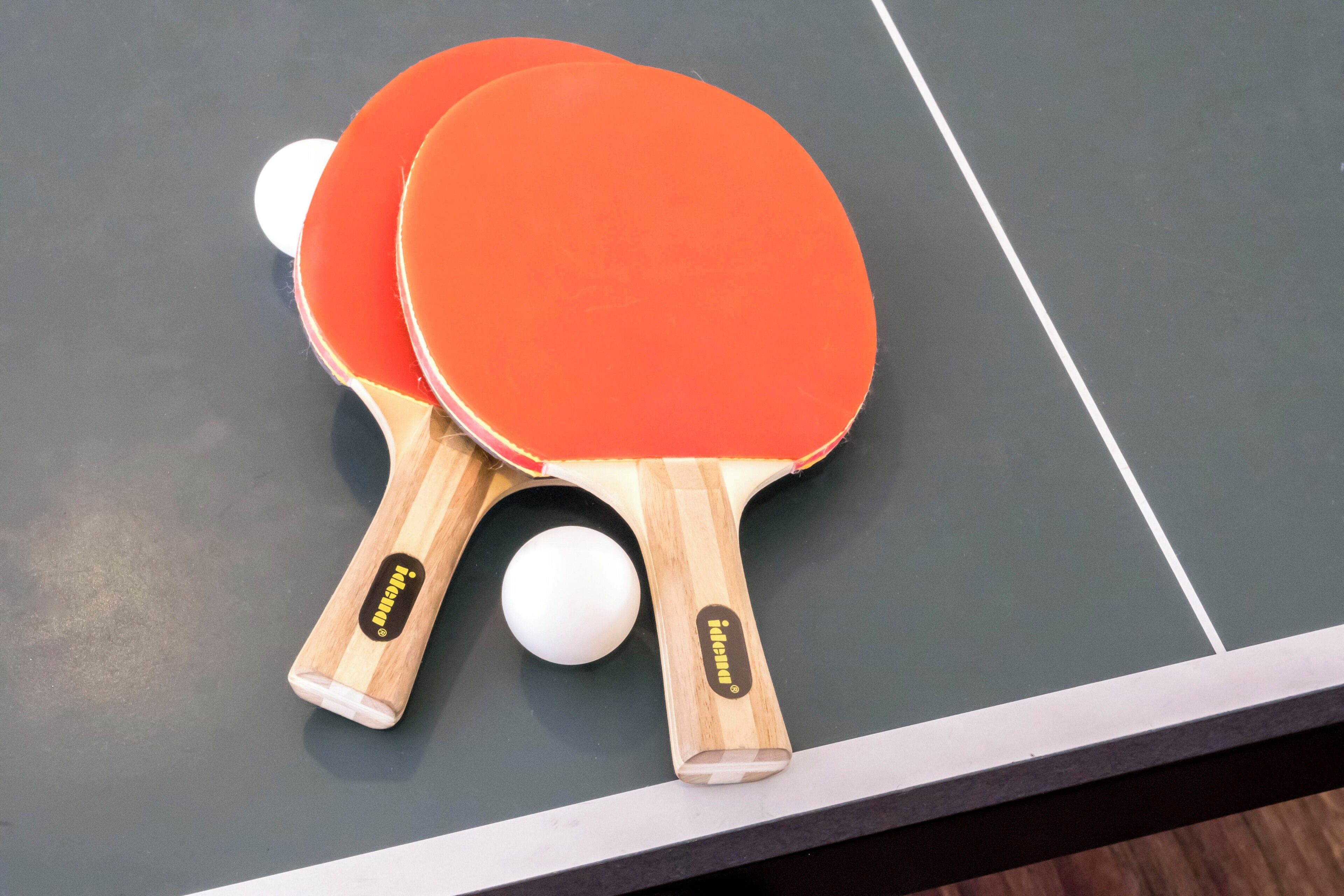 Zwei Tischtennis Schläger und ein Ball auf einem Tisch.
