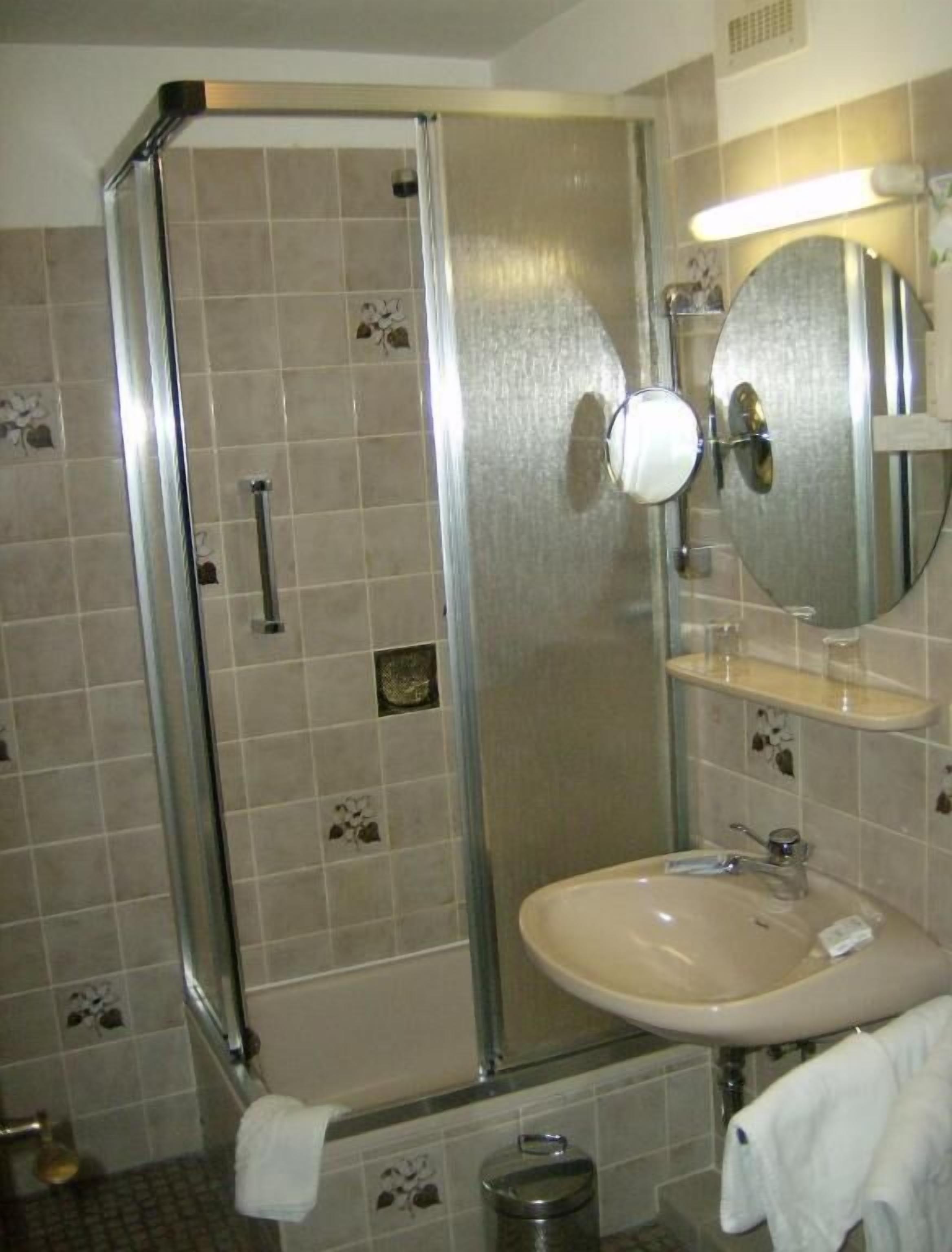 A bathroom with a glass-enclosed shower, a sink, and a mirror.