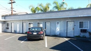 A building with a parking lot and a car parked in front. - El Grande Motel (South Gate)