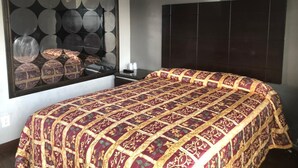 A bedroom with a large bed, a dark headboard, and a wall with circular mirrors. - El Grande Motel (South Gate)