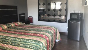 A modern hotel room with a large bed, a TV, and a small kitchenette. - El Grande Motel (South Gate)