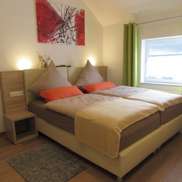 Un dormitorio moderno con una cama grande, mesitas de noche y un ventanal con cortinas.