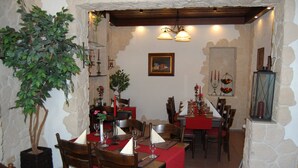 A dining area with stone walls, wooden tables, and chairs. There are potted plants and candles on the tables. - Eifel Quartier Em Garstüffje (Mechernich)