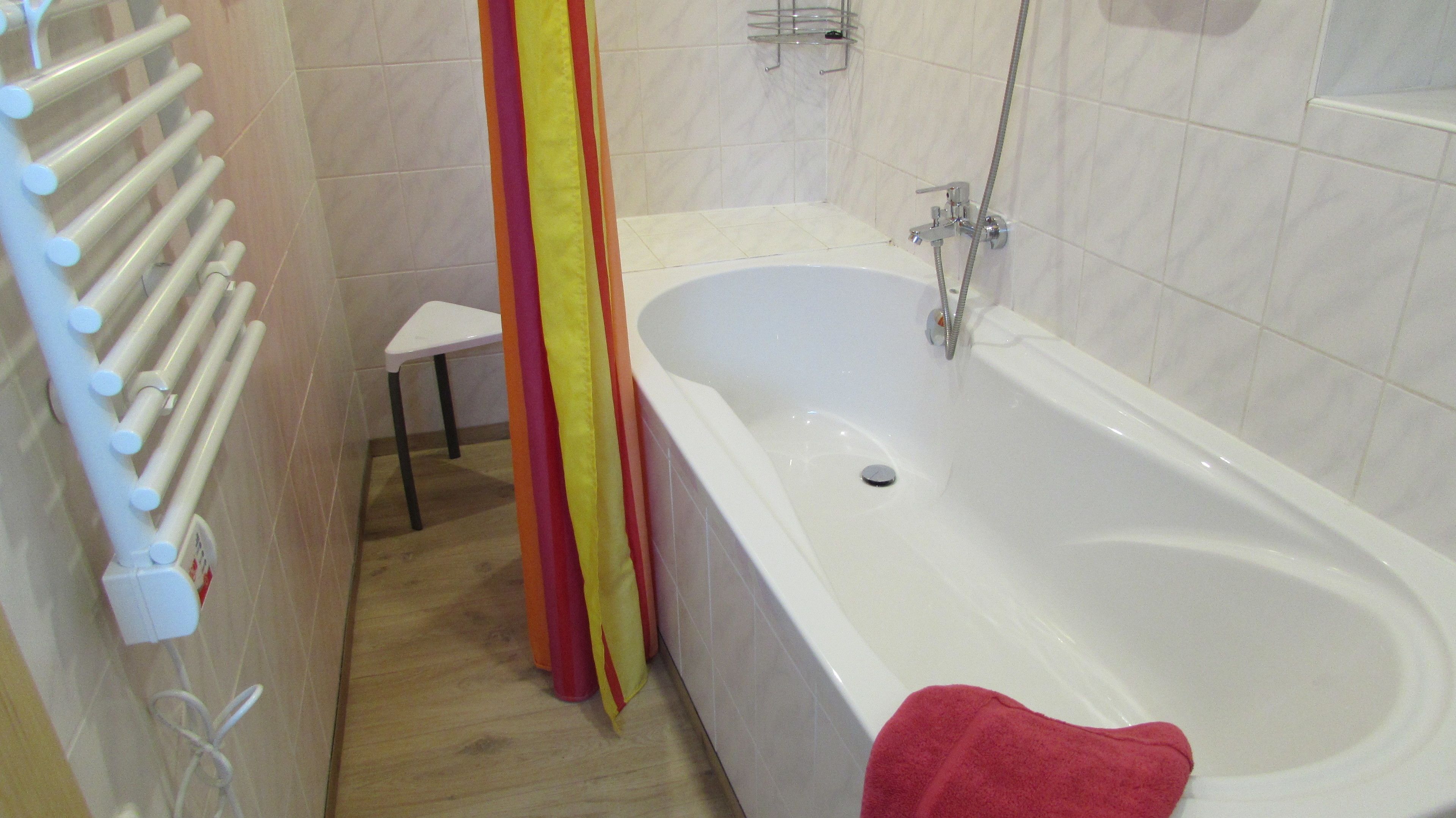 Ein Badezimmer mit einer weißen Badewanne, einer Dusche, einem weißen Handtuch und einem Handtuchhalter.