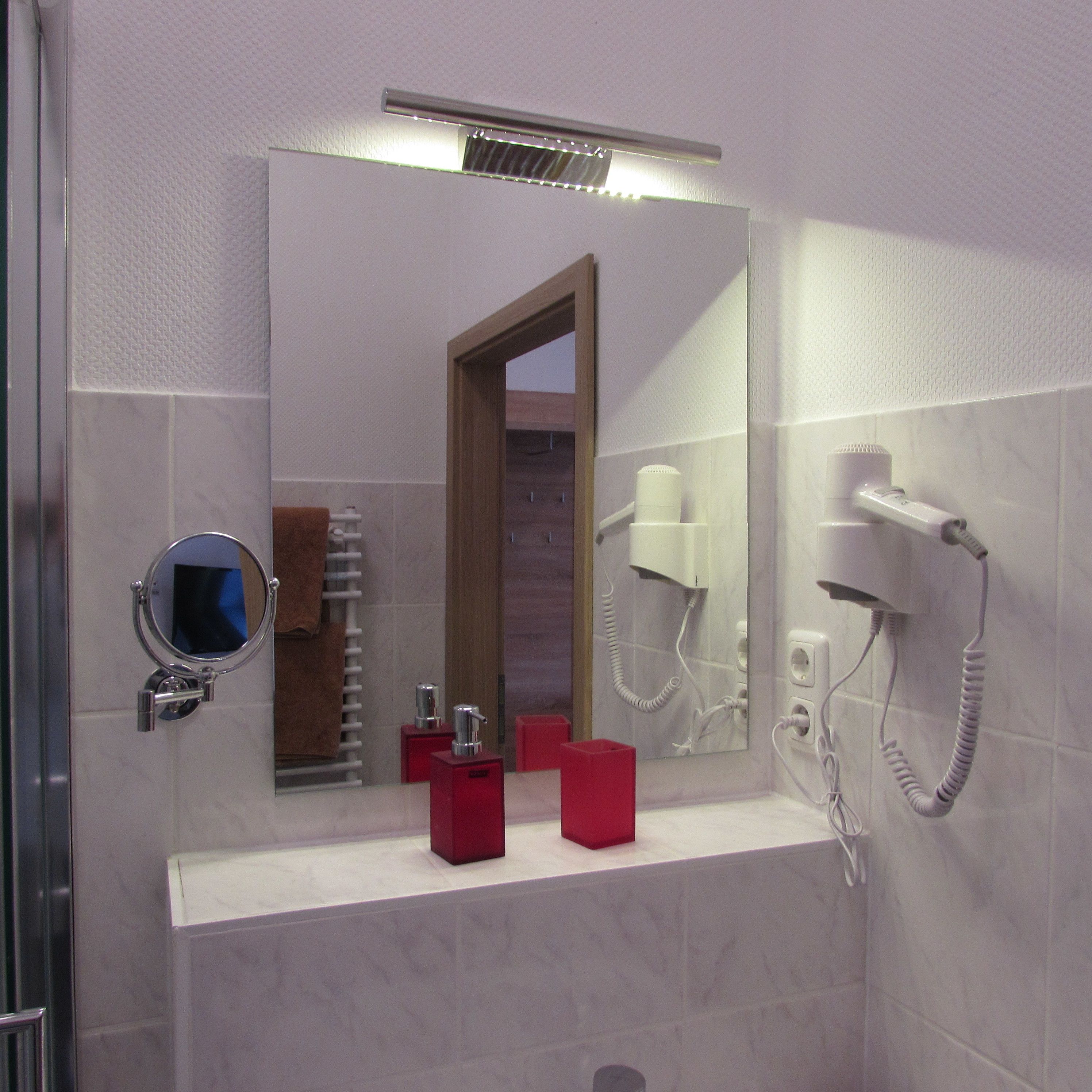 Une salle de bain équipée d’un miroir, d’un sèche-cheveux et d’un porte-serviettes.