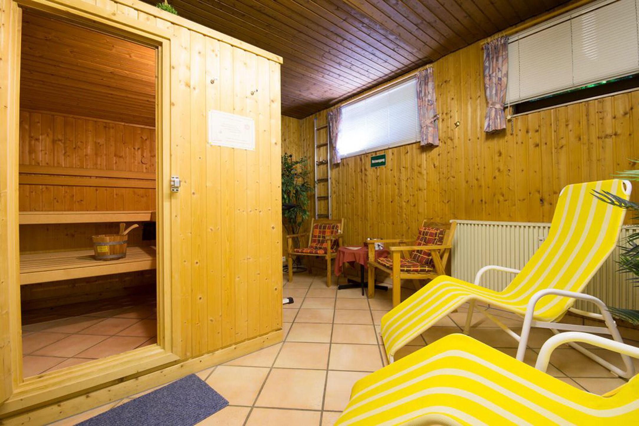 Un sauna de madera con puerta de madera, un banco y una mesa con sillas.