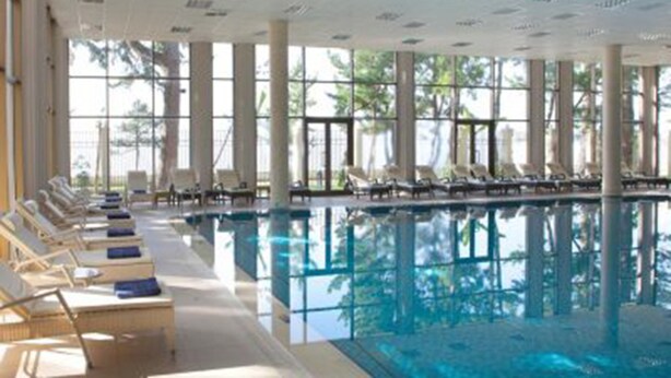 A large indoor swimming pool with lounge chairs and sunbeds along the sides. - Zeleny Dom (Kobuleti)