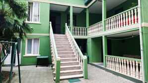 A multi-level building with green exterior walls, a staircase, and a balcony with white balustrades. - Zeleny Dom (Kobuleti)