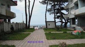 A pathway leading to a body of water, flanked by buildings and trees. - Zeleny Dom (Kobuleti)