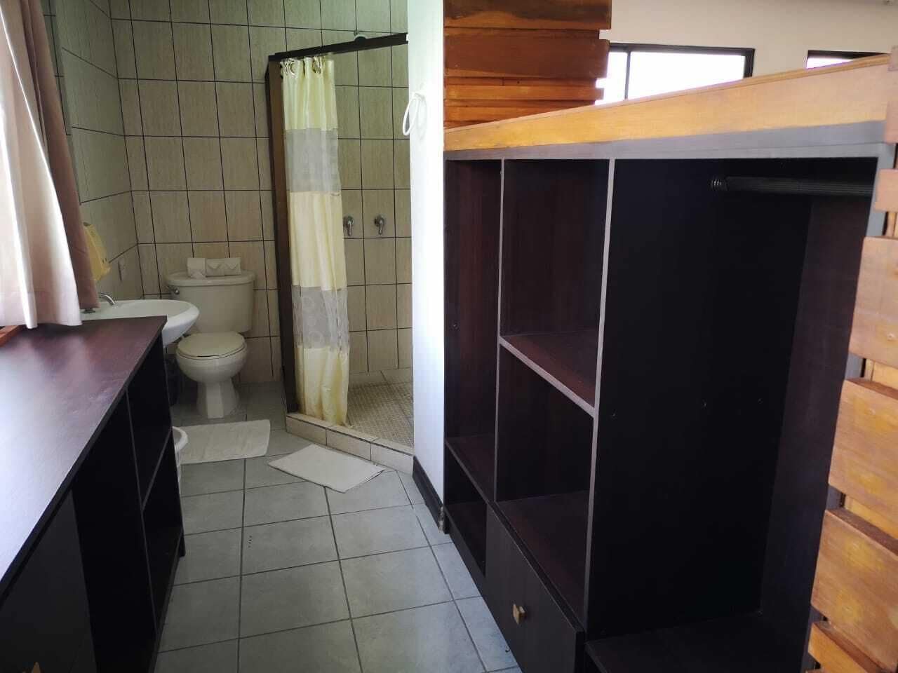 A bathroom with a toilet, shower, and wooden cabinets.