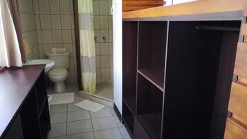 A bathroom with a toilet, shower, and wooden cabinets.