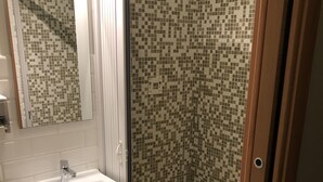 A bathroom with a white sink, mirror, and shower with mosaic tile walls. - Rent Rooms Colosseum (Rome)