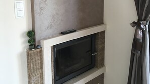 A modern living room with a fireplace, a mounted TV, and a small potted plant. - AM Beach House near Sea (Nea Propontida)