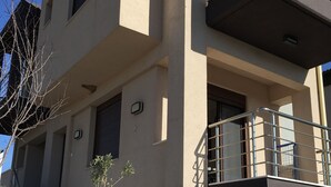 A modern two-story building with a flat roof, a balcony on the upper floor, and a small tree in the front yard. - AM Beach House near Sea (Nea Propontida)