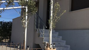 A modern outdoor area with a pergola, two large planters, and a staircase leading to an upper level. - AM Beach House near Sea (Nea Propontida)