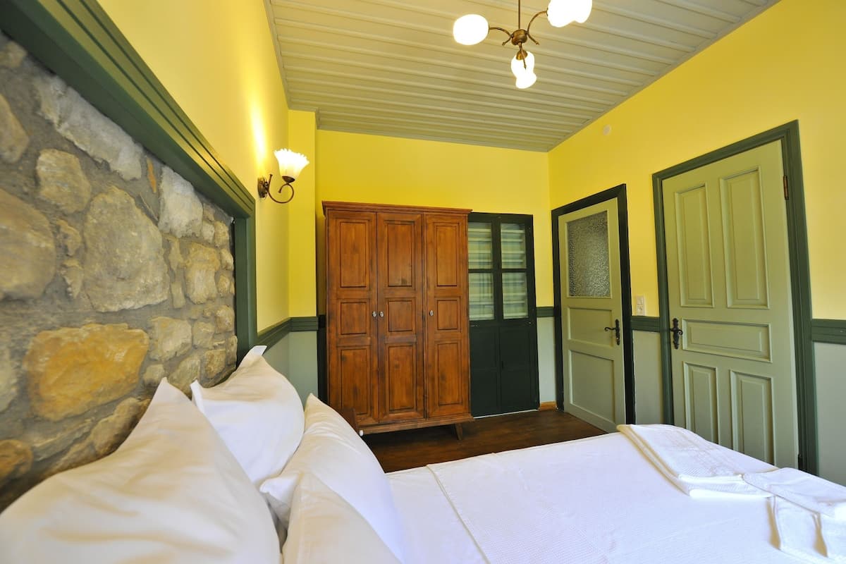 A bedroom with a stone wall, wooden wardrobe, and two doors.