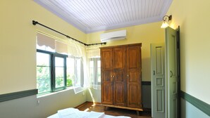 Quarto com cama, janela com cortinas, guarda-roupa e aparelho de ar condicionado.