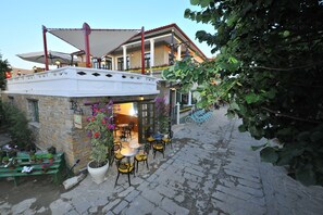 A café with outdoor seating, stone walls, and potted plants. - Petrino Gokceada Hotel & Kitchen (Gökçeada)
