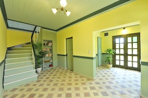 A hallway with a staircase, a bookshelf, and a door. - Petrino Gokceada Hotel & Kitchen (Gökçeada)