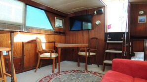 Un espace de vie compact avec un canapé rouge, des meubles en bois, un téléviseur et un tapis à motifs.