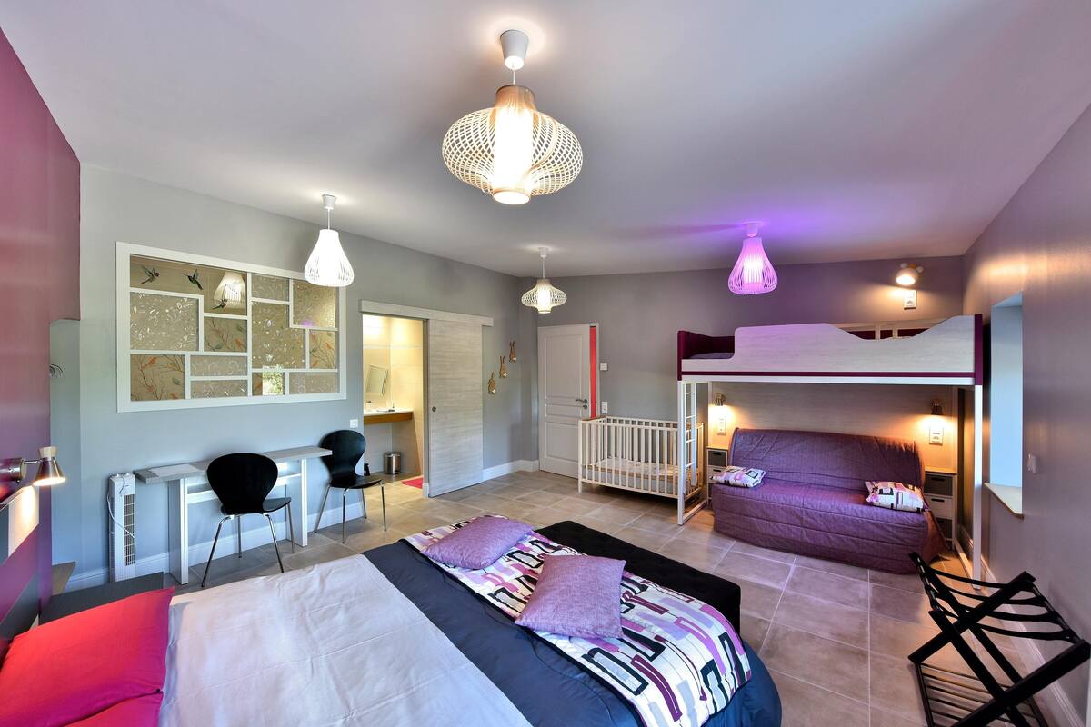 A modern bedroom with a bunk bed, a desk, and a crib.