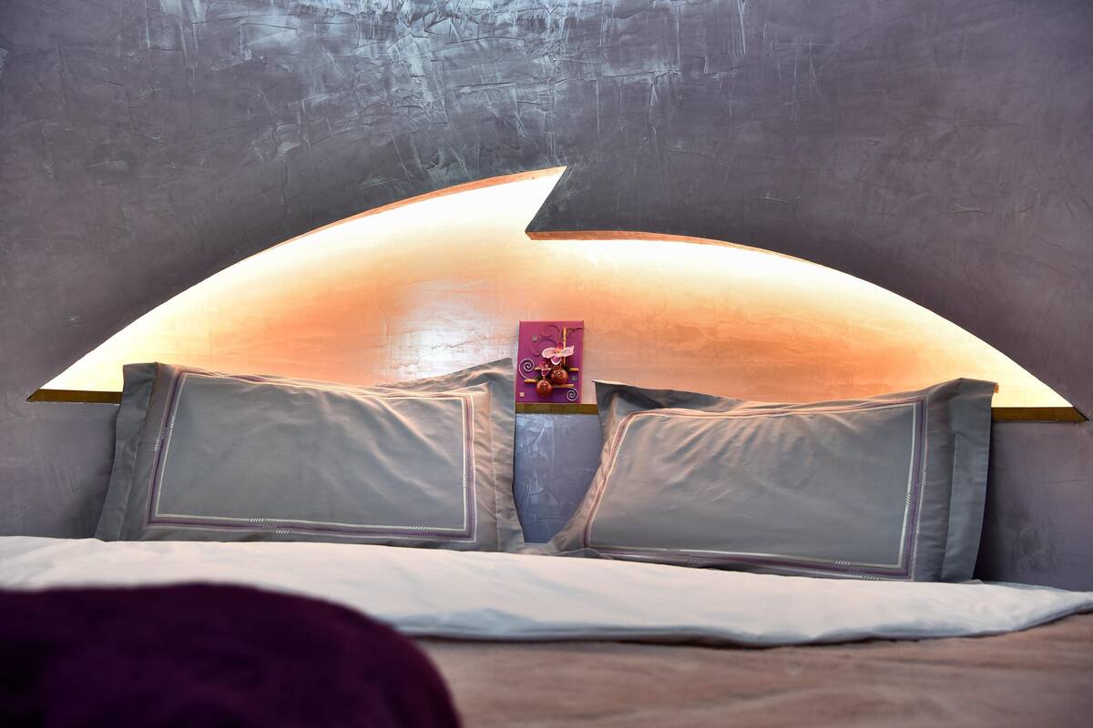 A bed with a unique curved headboard and a small decorative item on it.