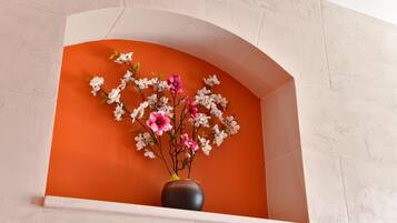 Een vaas met bloemen in een witte nis tegen een oranje muur.