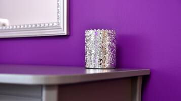 Un vase métallique au décor complexe, posé sur une surface incurvée devant un mur violet.