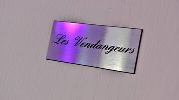 Una placa metálica con la inscripción 'Les Vendangeurs' en una pared de color claro.