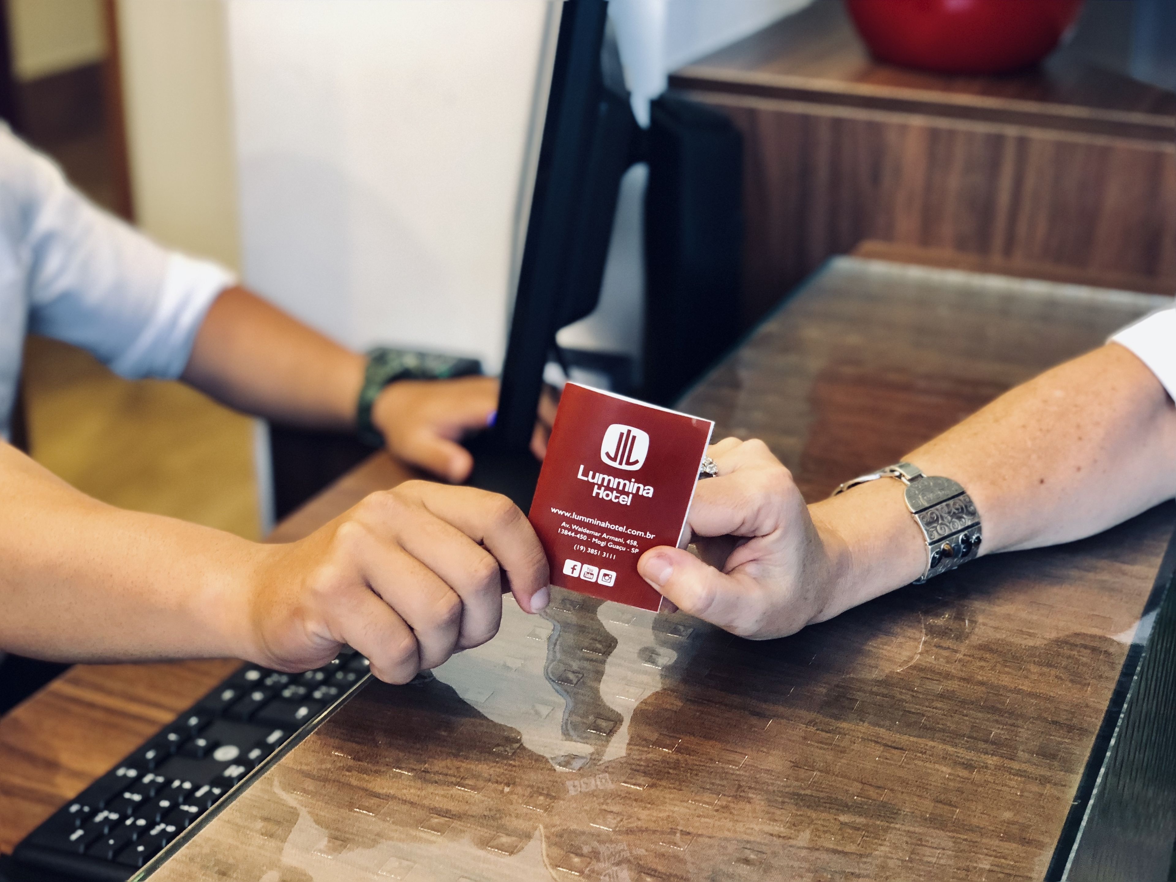 A person holding a red card with the Lummina Hotel logo and website address.