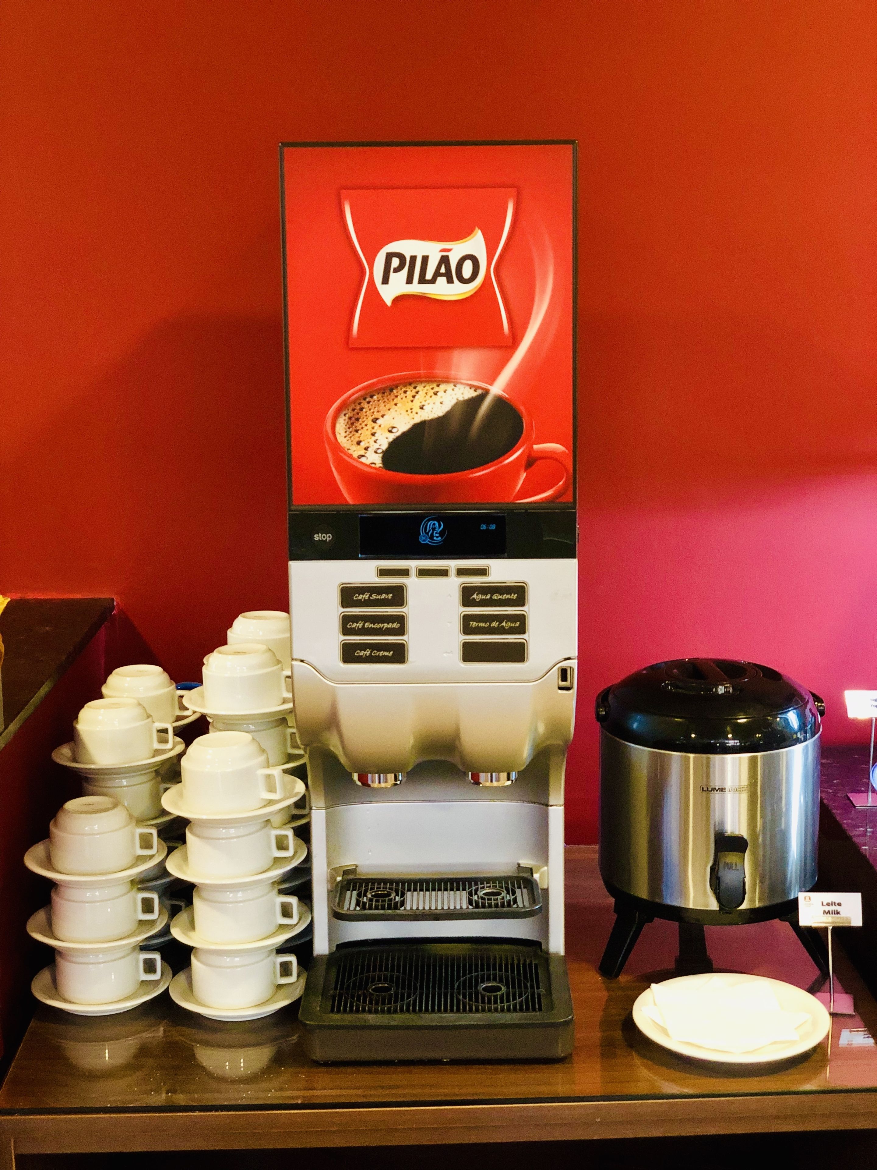 Máquina de café com diversas opções de chávena e dispensador de leite.